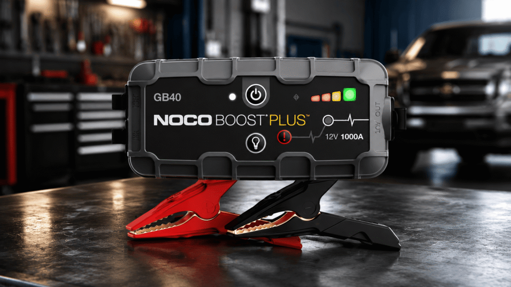NOCO Boost GB40 1000A vehicle battery jump starter with clamps on a workbench in a garage setting